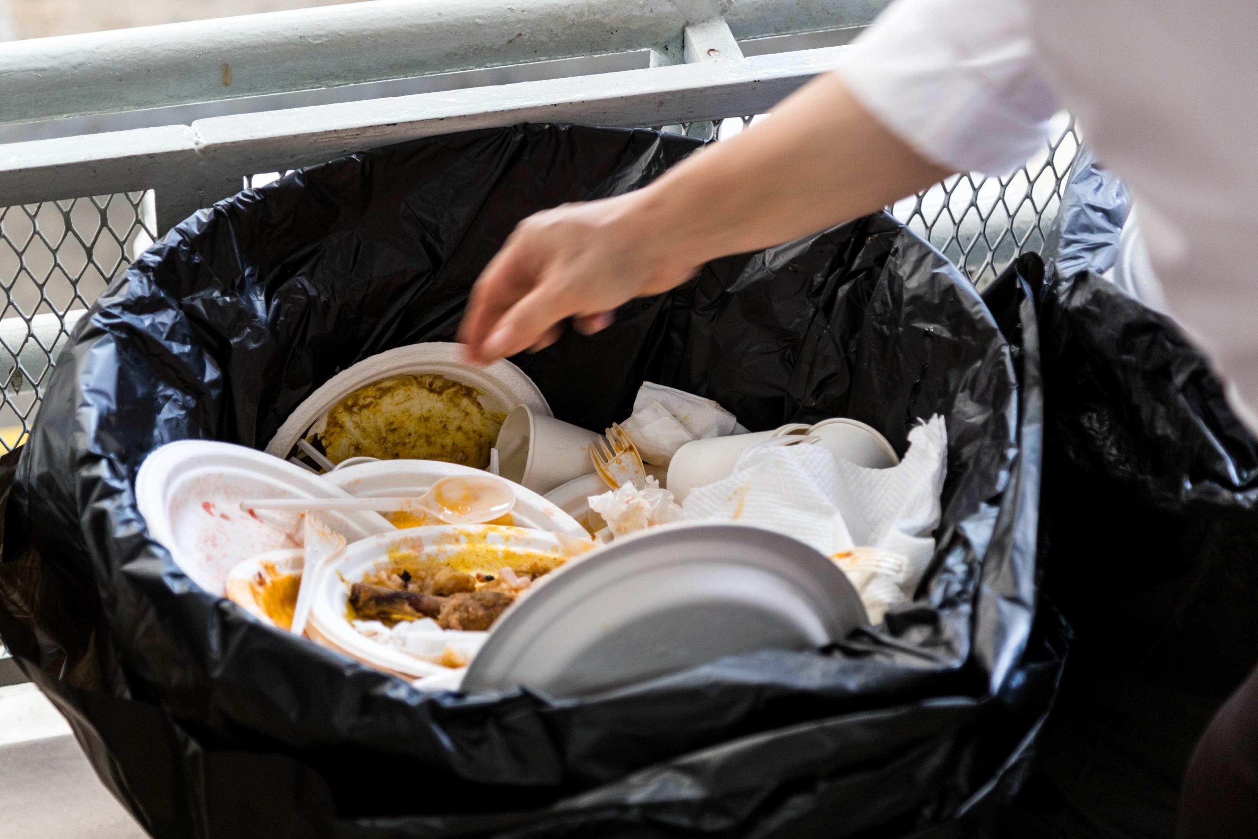 Assiettes et gobelets en polystyrène jetés dans un sac poubelle avec des déchets alimentaires